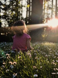girl sitting in stillness on daisy flowerbed in forest