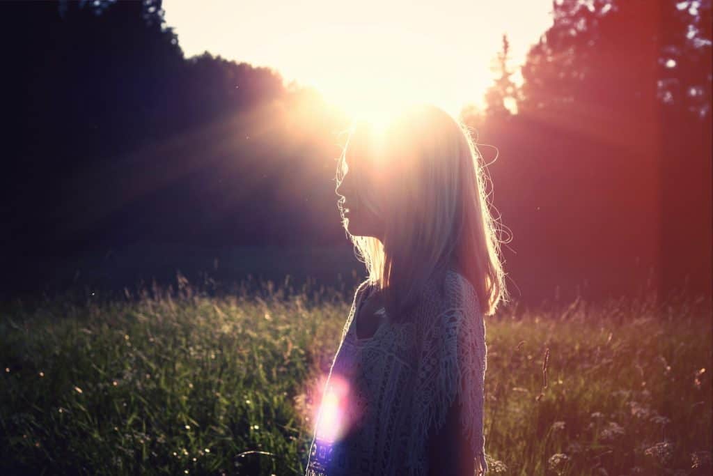 Woman meditating in golden sunlight embracing Leo season spiritual energy