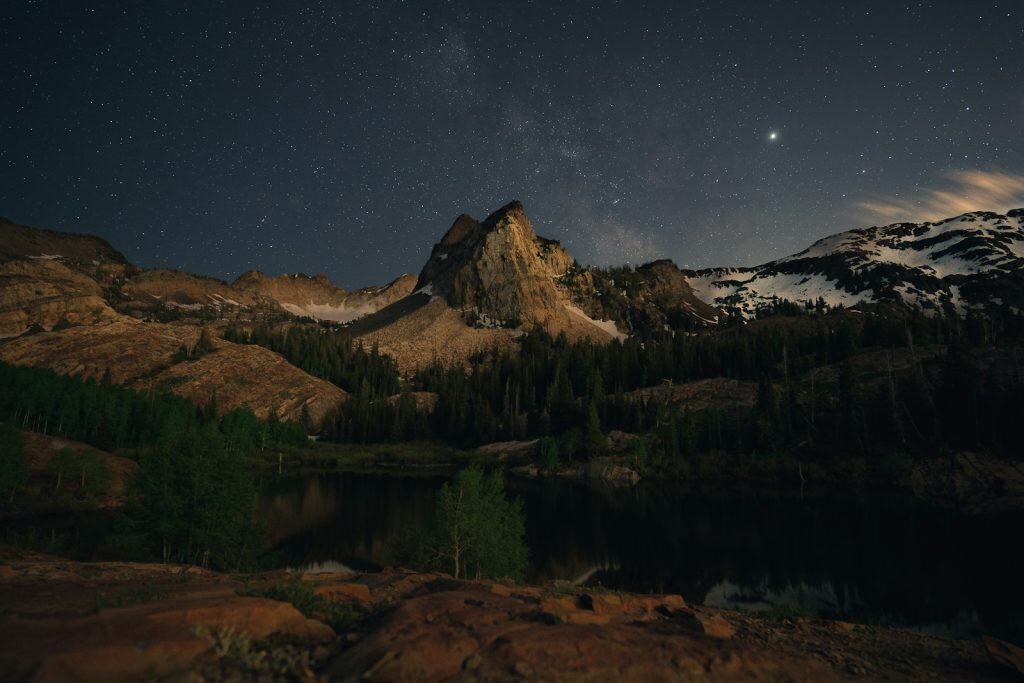 trees, lake, and mountain at night with the star Sirius visible