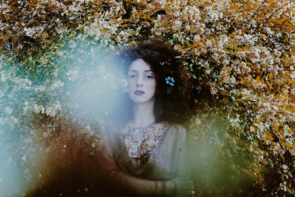 woman standing under floral plant highlighting her sacred archetype