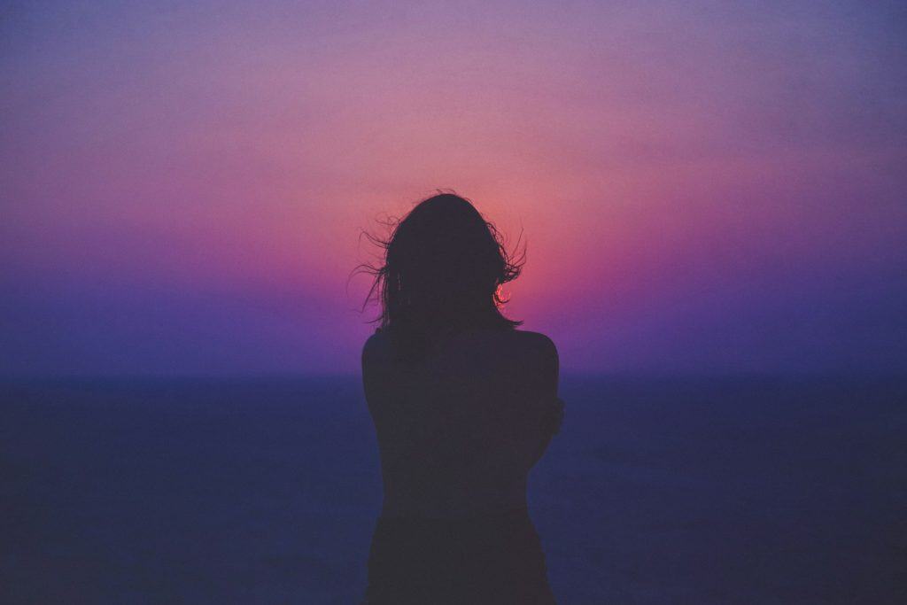 silhouette of a woman with pink and purple sky feeling the effects of spiritual breakthrough integration practice