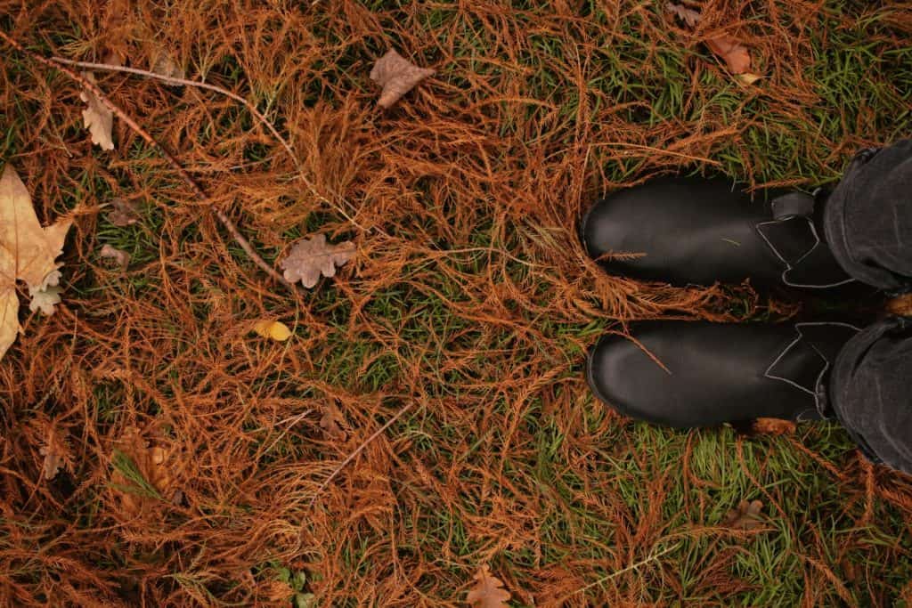 a person standing in the grass wearing black boots. Grounding back-to-school energy