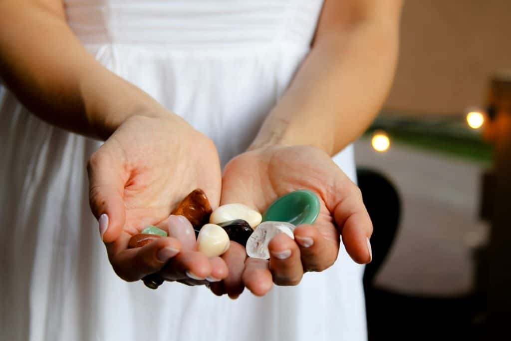 woman holding assorted-color crystals, a powerful tool for spiritual energy cleansing.