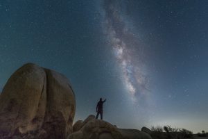 man standing on rock formation under blue sky during daytime trying to connect with Sirius